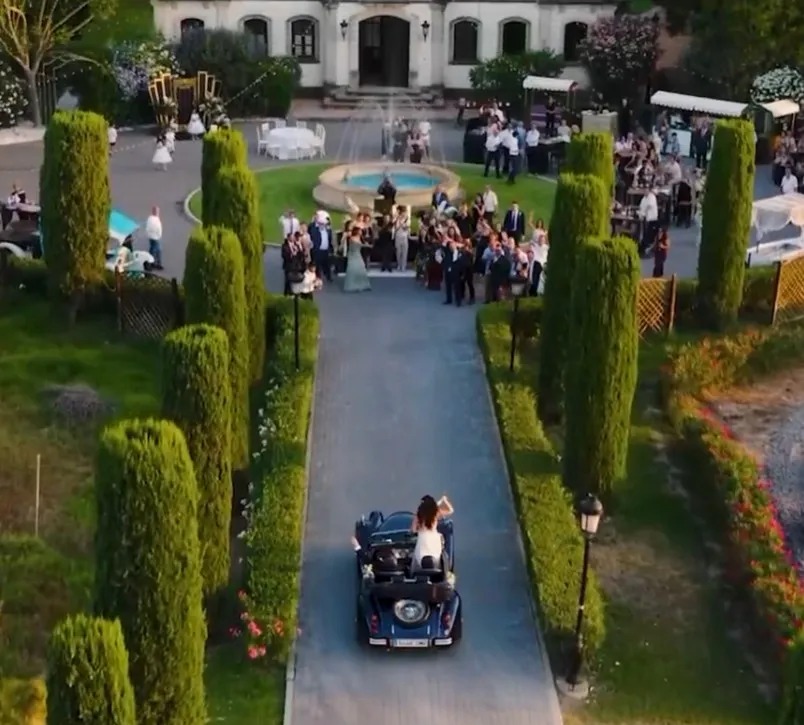 Dron siguiendo a los novios en coche clásico hacia la finca