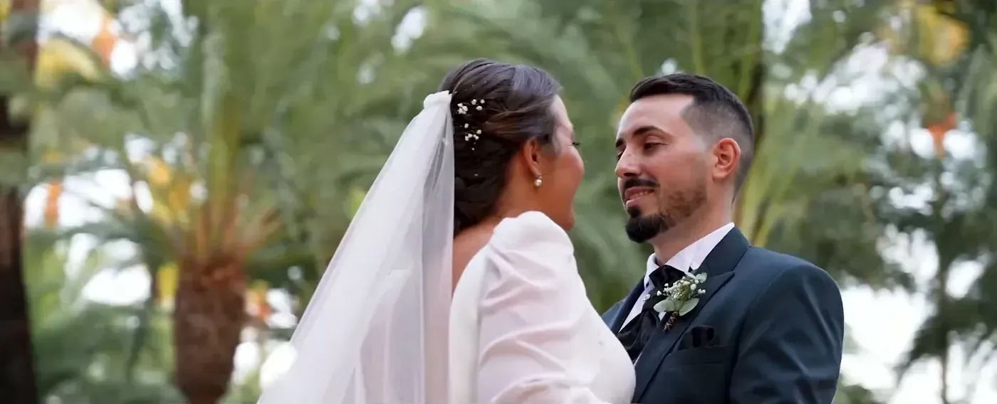 Bride and groom smiling at each other under palm trees