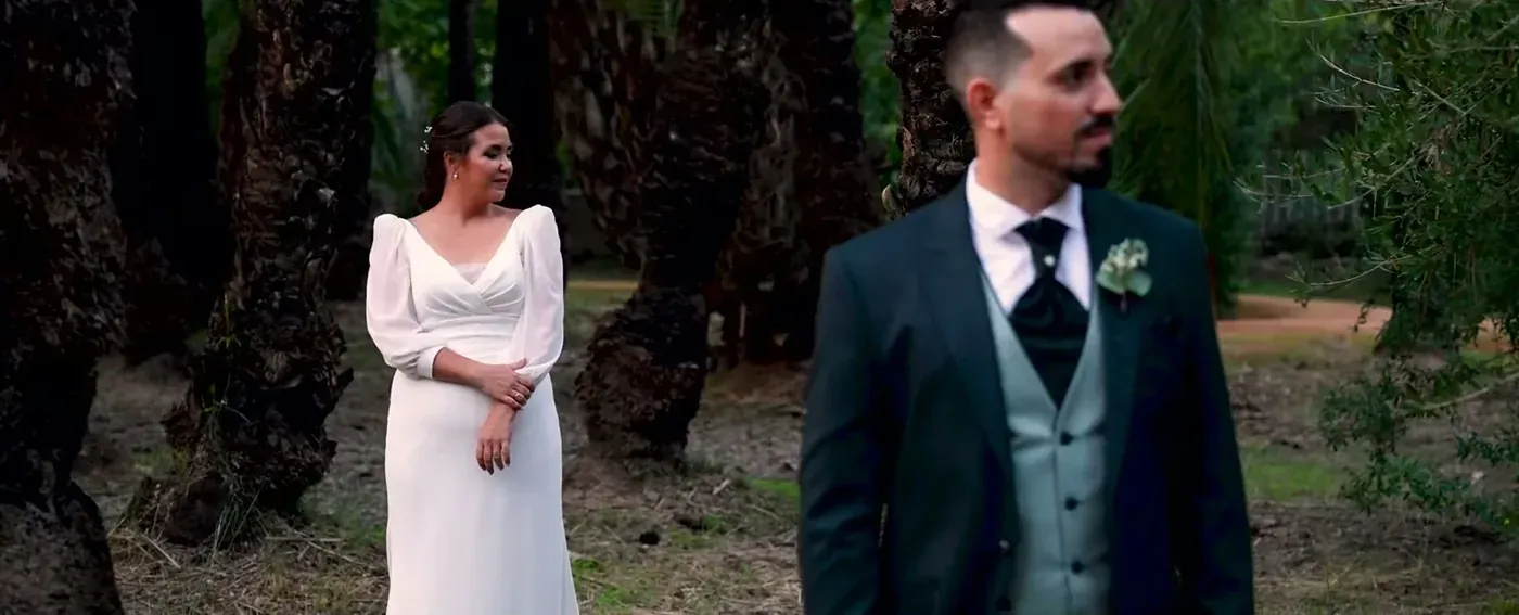 Bride and groom standing among tall palm trunks