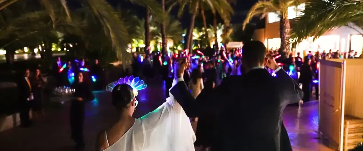 Wedding party under palm trees at night with glowing lights