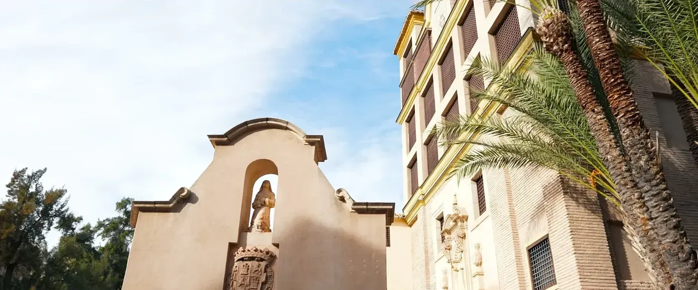 Bell gable of a historic church among palm trees under a blue sky
