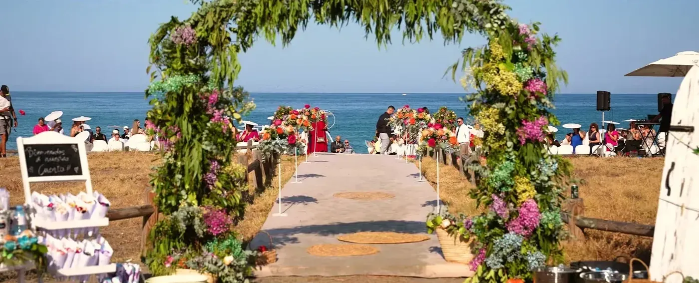Flower arch framing the sea at a beachside wedding ceremony