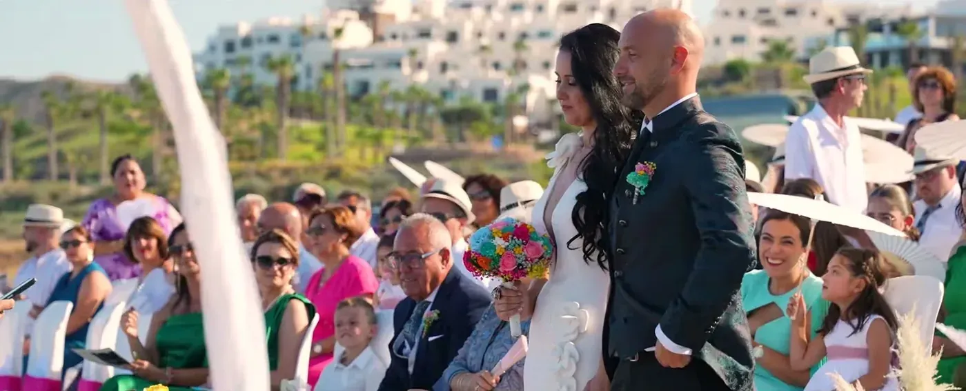 Bride and groom standing before their guests at a seaside ceremony