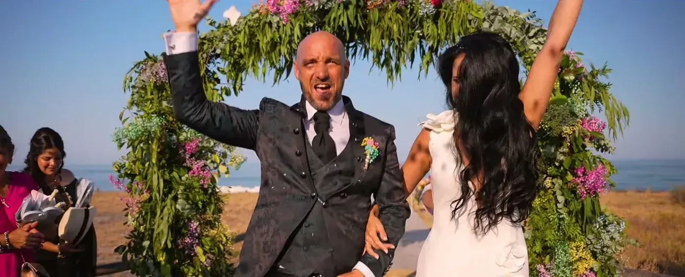 Newlyweds celebrating under a flower arch with the sea behind them