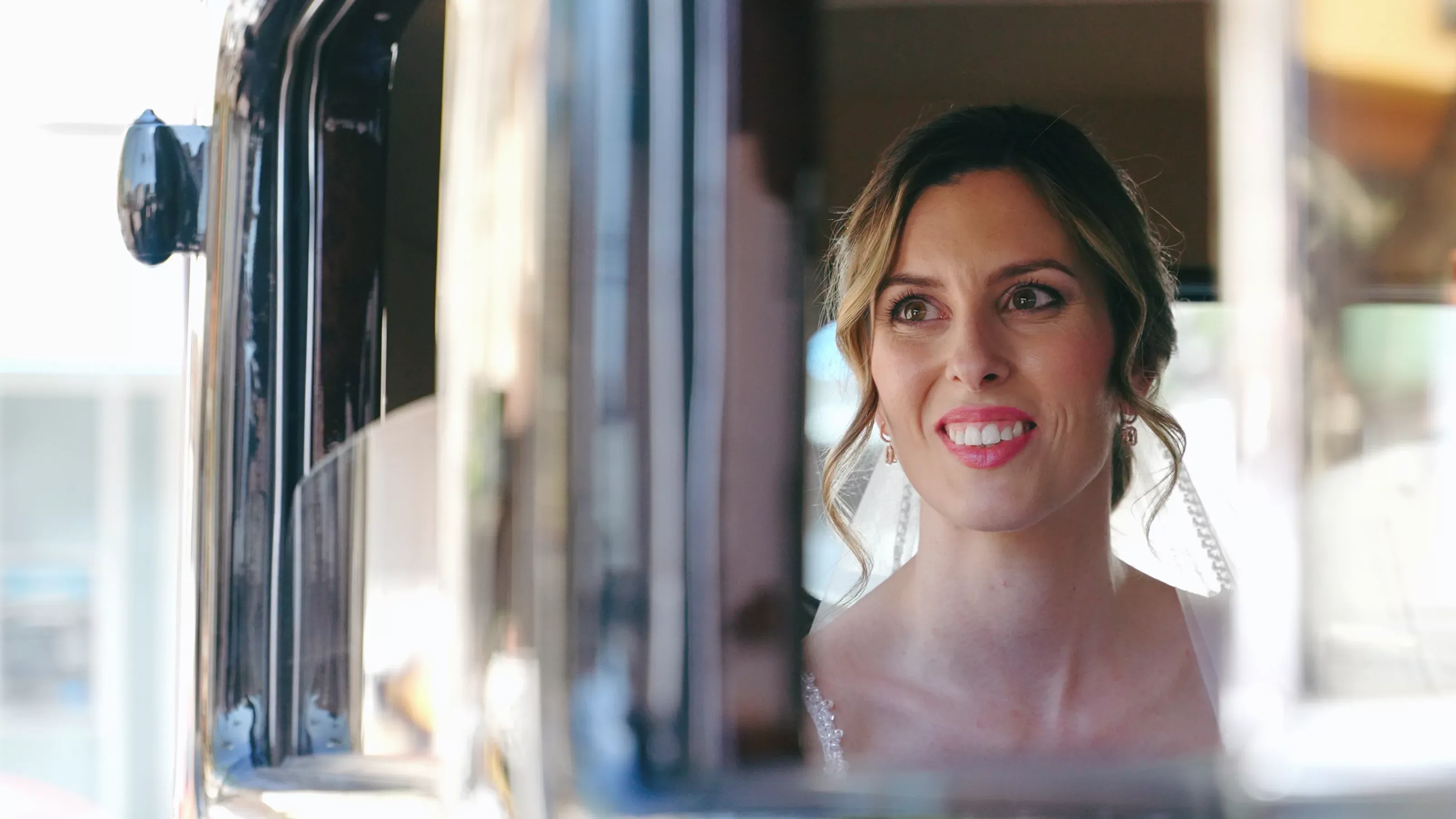 Novia sonriendo desde la ventanilla de un coche antiguo