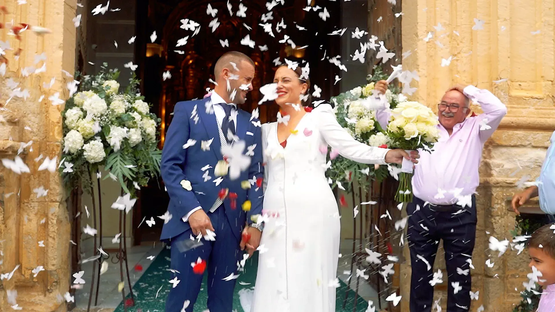 Couple leaving a stone church under paper confetti